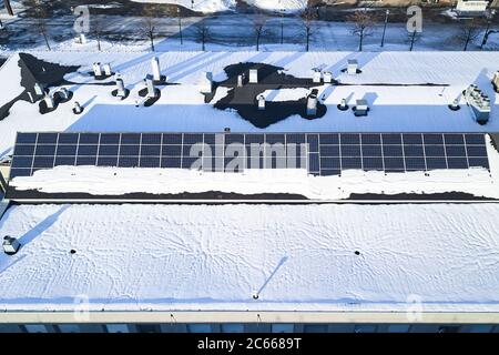 Luftaufnahme von verschneiten Solarzellen auf dem Dach eines Mehrfamilienhauses. Stockfoto