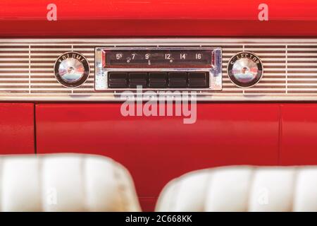 Altes Autoradio in einem roten klassischen amerikanischen Auto mit Chrom-Armaturenbrett Stockfoto