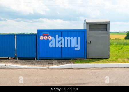 Eingezäunter blauer Müllcontainer mit Feuerschildern aus nächster Nähe Stockfoto