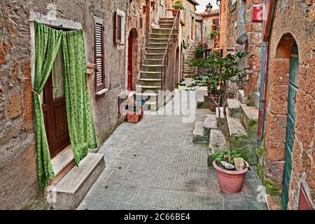 Pitigliano, Grosseto, Toskana, Italien: Alte Gasse mit alten Häusern und Pflanzen in der malerischen mittelalterlichen Stadt Stockfoto