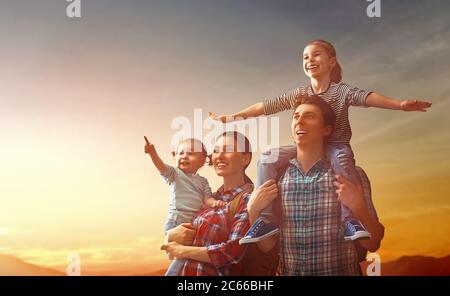 Glückliche Familie bei Sonnenuntergang. Vater, Mutter und zwei Kinder Töchter Spaß und genießen Reise. Das Kind sitzt auf den Schultern seines Vaters. Stockfoto