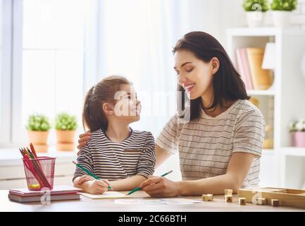 Frohe Familie. Mutter und Tochter lernen zu schreiben. Erwachsene Frau lehrt Kind das Alphabet. Stockfoto