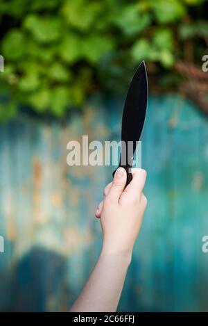 Schwarzes Messer zum Werfen in die Hand einer Frau, Spiel für aktive Erholung Stockfoto