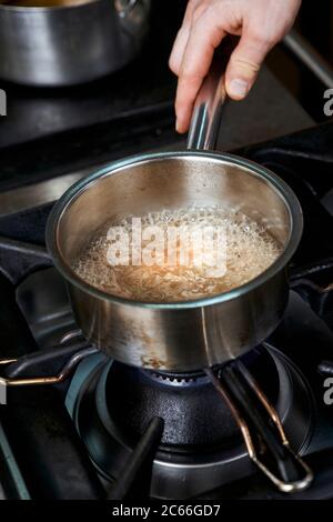 Zubereitung von Béarnaise Sauce Schritt für Schritt, Wein und Essig sowie gehackte Schalotten und Kräuter gekocht werden Stockfoto