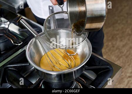 Zubereitung der Béarnaise Sauce Schritt für Schritt, Reduktion durch ein Sieb belastet Stockfoto