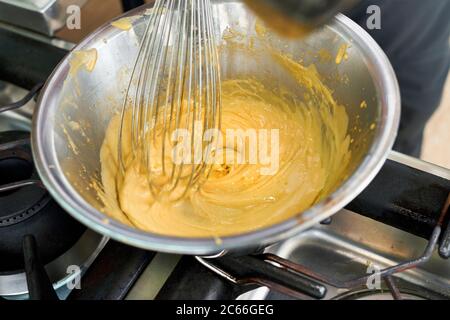 Zubereitung von Béarnaise Sauce Schritt für Schritt, geklärt Butter wird sanft auf den Sabayon hinzugefügt Stockfoto
