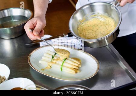Zubereitung von Spargel mit Béarnaise Sauce Schritt für Schritt, Spargelspieße auf einem Teller und Béarnaise Sauce darauf beträufelt Stockfoto