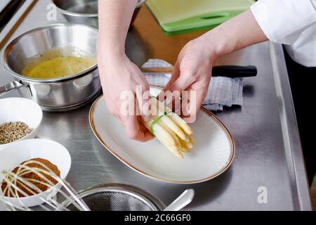 Zubereitung von Spargel mit Béarnaise Sauce Schritt für Schritt, Spargelspieße werden auf einem Teller angeordnet Stockfoto