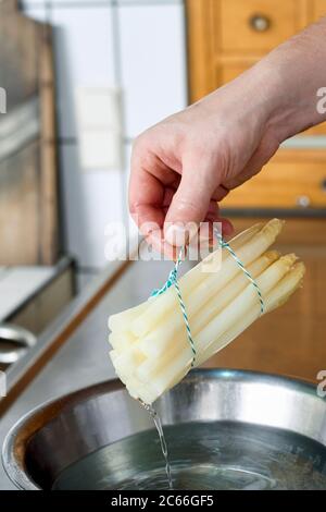 Zubereitung von Spargel mit Béarnaise Sauce Schritt für Schritt, Spargelspieße werden aus dem kochenden Wasser entfernt Stockfoto