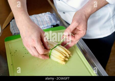 Zubereitung von Spargel mit Béarnaise Sauce Schritt für Schritt, Spargelspieße werden gebündelt mit Schnittlauch Stockfoto