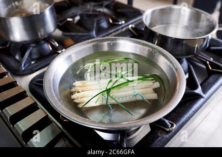 Zubereitung von Spargel mit Béarnaise Sauce Schritt für Schritt, gebündelte Spargelspieße in heißem Wasser Stockfoto