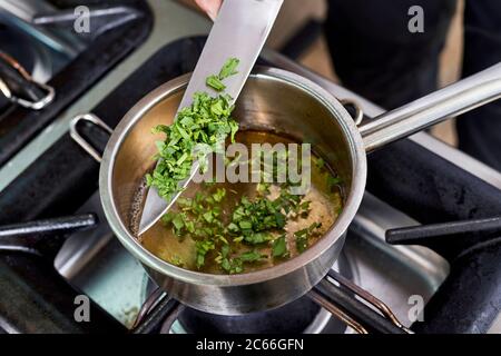 Zubereitung der Béarnaise Sauce Schritt für Schritt, fein gehackter Estragon wird hinzugefügt Stockfoto