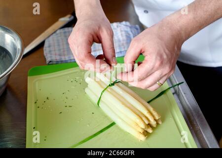 Zubereitung von Spargel mit Béarnaise Sauce Schritt für Schritt, Spargelspieße werden gebündelt mit Schnittlauch Stockfoto