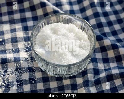 Fleur de Sel in einer kleinen Glasschale auf einer Tischdecke, blau-weiß kariert Stockfoto