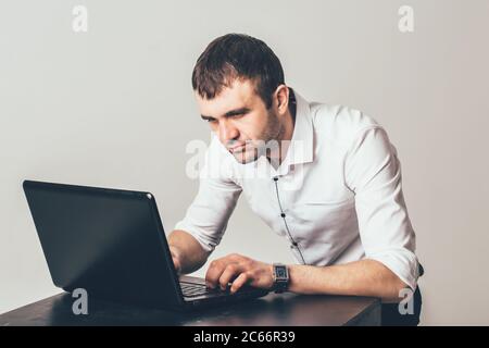 Ein vielbeschäftigter Mann arbeitet im Büro am Laptop. Der Unternehmer ist auf die Lösung der Aufgaben fokussiert. Stockfoto