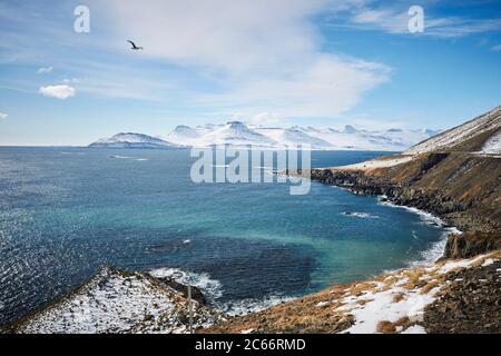 Island, Blick auf die Ostfjorde, verschneite Berge in der Ferne, blauer Himmel Stockfoto