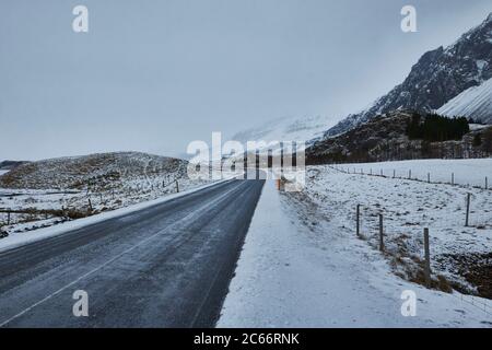 Straße durch schneebedeckte isländische Berge, Ostfjorde, Fenkeline Stockfoto