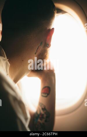 Junger Mann, der aus dem Fenster eines Flugzeugs schaut Stockfoto