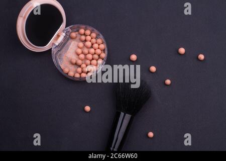 Face Puder Make-up Kugeln und schwarze Bürste auf schwarzem Hintergrund. Stockfoto