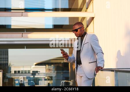 Afroamerikanischer Geschäftsmann mit Handy an einem Sommernachmittag. Stockfoto