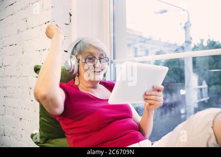 Gewinner. Reife Frau verbringt Zeit in Quarantäne - kaukasierinnen Frau mit modernen Gadgets, Tee trinken. Augen müde von Gadgets. Interessiert und Spaß haben. Copyspace auf leerem Bildschirm. Lifestyle. Stockfoto