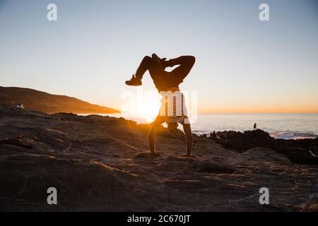 Handstand am Strand bei Sonnenaufgang Stockfoto