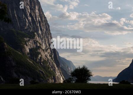 Abends ein schöner Fjord-Talblick, umgeben von Bergen, bewölktem blauem Himmel. Stockfoto