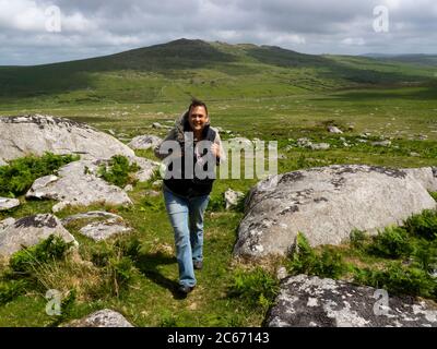 Frau, die auf Bodmin Moor läuft, mit Brown Willy Tor im Hintergrund, Cornwall, Großbritannien Stockfoto