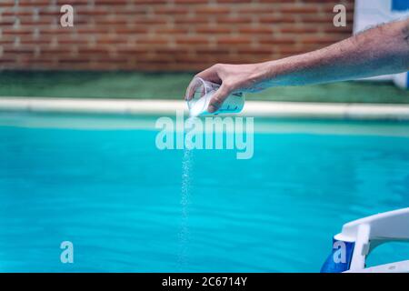 Person Reinigung und Chlorierung des Pools an einem heißen Sommernachmittag, läuft der Reiniger und Zugabe von Chlor-Pulver Stockfoto