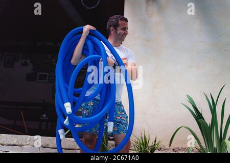 Person Reinigung und Chlorierung des Pools an einem heißen Sommernachmittag, läuft der Reiniger und Zugabe von Chlor-Pulver Stockfoto
