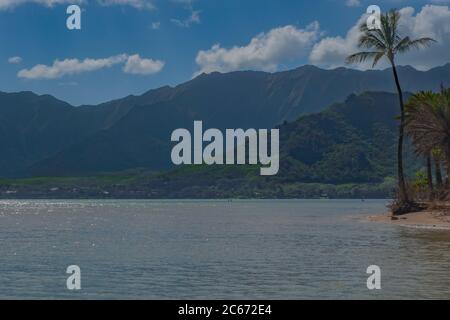 Ruhiger Pazifischer Ozean mit üppigen Bergen und Palmen auf Oahu Hawaii Stockfoto