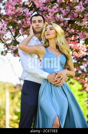 Angenehme Zeit verbringen. Paar in der Liebe Kuss und Umarmung. Frühlingsblumenblüte. Mann und Frau im Park mit rosa blühenden Kirsche. Schönheit und Mode. Süße Flitterwochen. Romantisches Paar unter Sakura Baum. Stockfoto