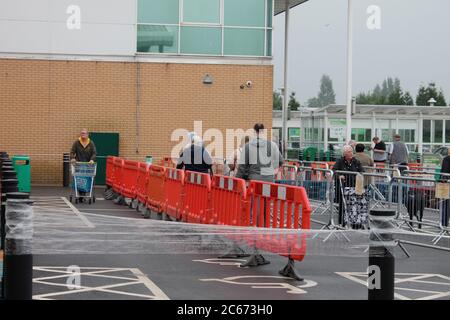 Menschen soziale Distanzierung in einer Warteschlange, um einen Supermarkt zu betreten Stockfoto