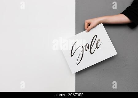 Nahaufnahme Foto von Frau Hand hält coole Postkarte auf grauem Hintergrund Stockfoto