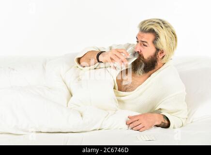 Hipster trinken Wasser Nehmen Sie Medikamente. Kopfschmerz Kater. Kater Heilmittel. Kater-Konzept. Mann schmerzhaft Leiden Gesicht Aufwachen am Morgen. Überschlafen kann Körper in Gefahr für metabolische Probleme setzen. Stockfoto