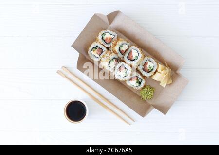 Nehmen Sie asiatische Lebensmittel Sushi-Rollen in sushis Karton Bio-Box auf weißem Holzhintergrund Stockfoto