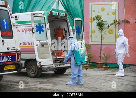 Arbeiter sprüht Desinfektionsmittel auf einen Krankenwagen, nachdem sie Patienten in einem provisorischen COVID-19 Krankenhaus auf dem Khanapara Veterinary Ground während der totalen Sperre, die von der Assam-Regierung zur Eindämmung der Ausbreitung des neuartigen Coronavirus am Freitag, den 03. Juli 2020 in Guwahati, Assam, Indien, verhängt wurden. Stockfoto