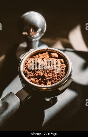 Gemahlener Kaffee in einem Portafilter und einer Kaffeepulver. Interessantes Licht. Stockfoto