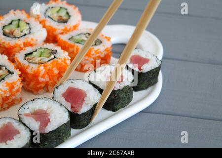 Japanisches Sushi-Set mit Essstäbchen aus nächster Nähe auf dem grauen Holztisch Stockfoto