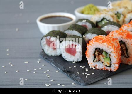 Nahaufnahme von Sushi-Set mit Sojasauce und Wasabi. Asiatische Küche auf Steinbrett und grauem Holzhintergrund Stockfoto
