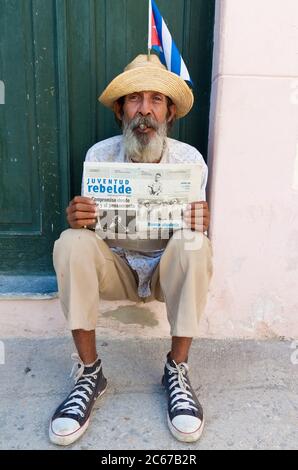 Alter Mann in Havanna, der eine Zeitung hält und eine kubanische Zigarre raucht Stockfoto