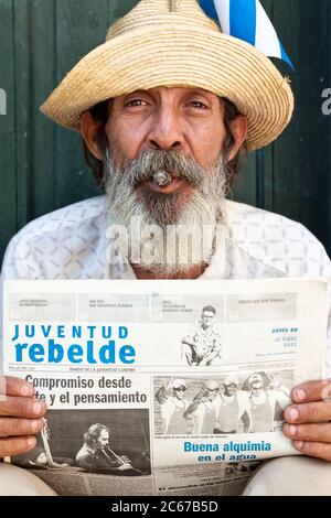 Alter Mann in Havanna, der eine Zeitung hält und eine kubanische Zigarre raucht Stockfoto