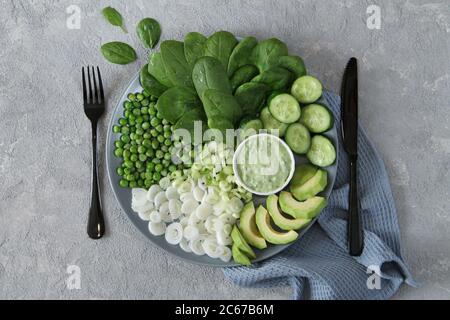 Frischer grüner vegetarischer oder veganer Salat auf grauem Steingrund, Draufsicht. Gesunde Ernährung Saubere Ernährung: Gemüse, Superfood, Blattgemüse. Buddha-Schale Stockfoto
