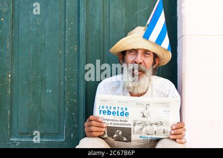 Alter Mann in Havanna, der eine Zeitung hält und eine kubanische Zigarre raucht Stockfoto