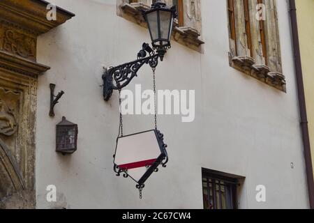 Geschmiedetes dekoratives schwarzes Schild mit Platz für Text und Logo an der Wand. Modell eines Restaurants oder eines Ladens mit weißen schmiedeeisernen Schildern an beigefarbenen Wänden. Stockfoto