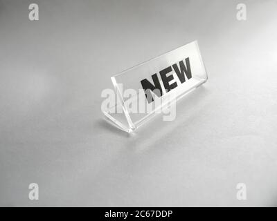 Die Inschrift neu einer Shop-Preisliste. Plastic Preisschild auf einem hellen Hintergrund für Waren oder Handel Stockfoto