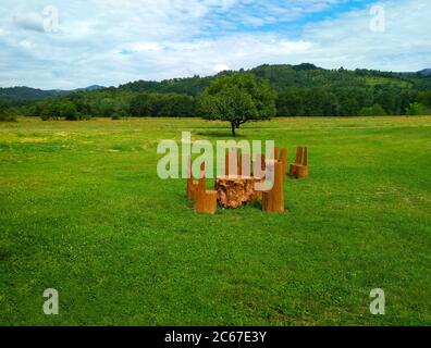 Tisch mit Massivholzstühlen auf einem grünen Rasen auf einem Hintergrund der Berge, Erholung im Freien Stockfoto