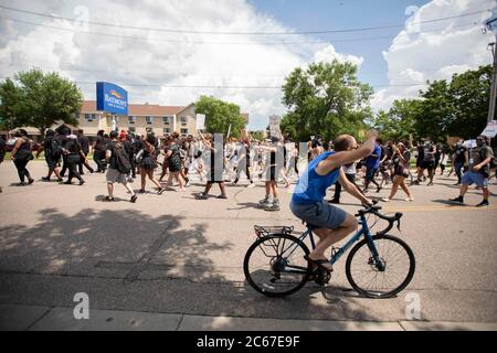 5. Juli 2020: Ein Mann, der mit dem Fahrrad fährt, hebt seine Faust solidarisch in die Luft, als er am Protestierenden vorbeigeht, während sie am 5. Juli 2020 in Bloomington, Minnesota, auf dem Weg zum George Floyd Square in Minneapolis in 95Â Hitze marschieren. (Bild: © Chris JuhnZUMA Wire) Stockfoto