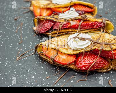 Crepes mit Erdbeere und Sahne und Schokolade auf Schieferplatte serviert Stockfoto