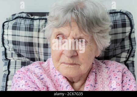 Porträt der alten älteren Frau mit Falten im Gesicht und grauen Haaren. Elderige Dame mit faltigen Gesicht. Nahaufnahme der Granmutter, die auf dem Stuhl sitzt. Oma por Stockfoto